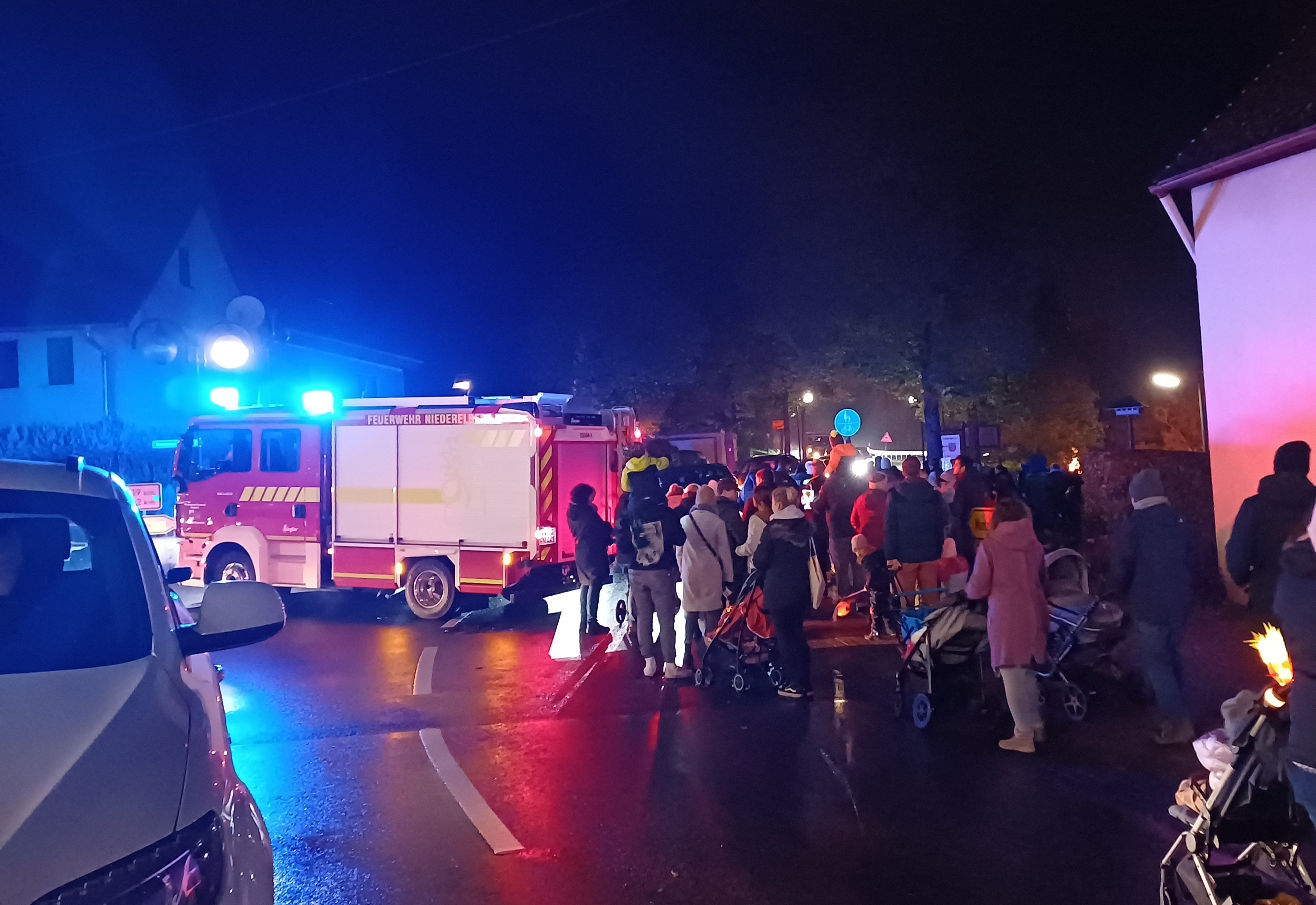 Menschen an der Haupstraße beim Martinsumzug, begleitet von einem Feuerwehrwagen
