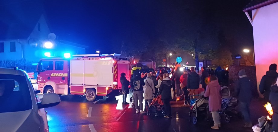 Menschen an der Haupstraße beim Martinsumzug, begleitet von einem Feuerwehrwagen