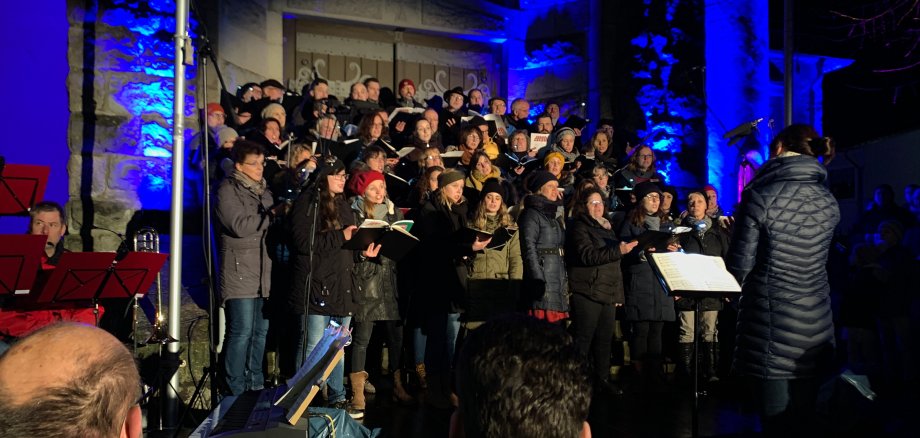 Chor steht vor einer erleucheten Kirche