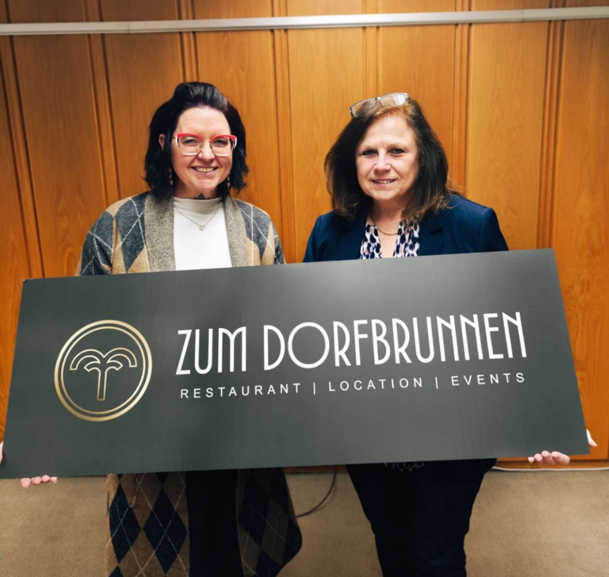 Michaela Rasch und Carmen Dietenhoven halten ein Schild mit dem neuen Logo hoch