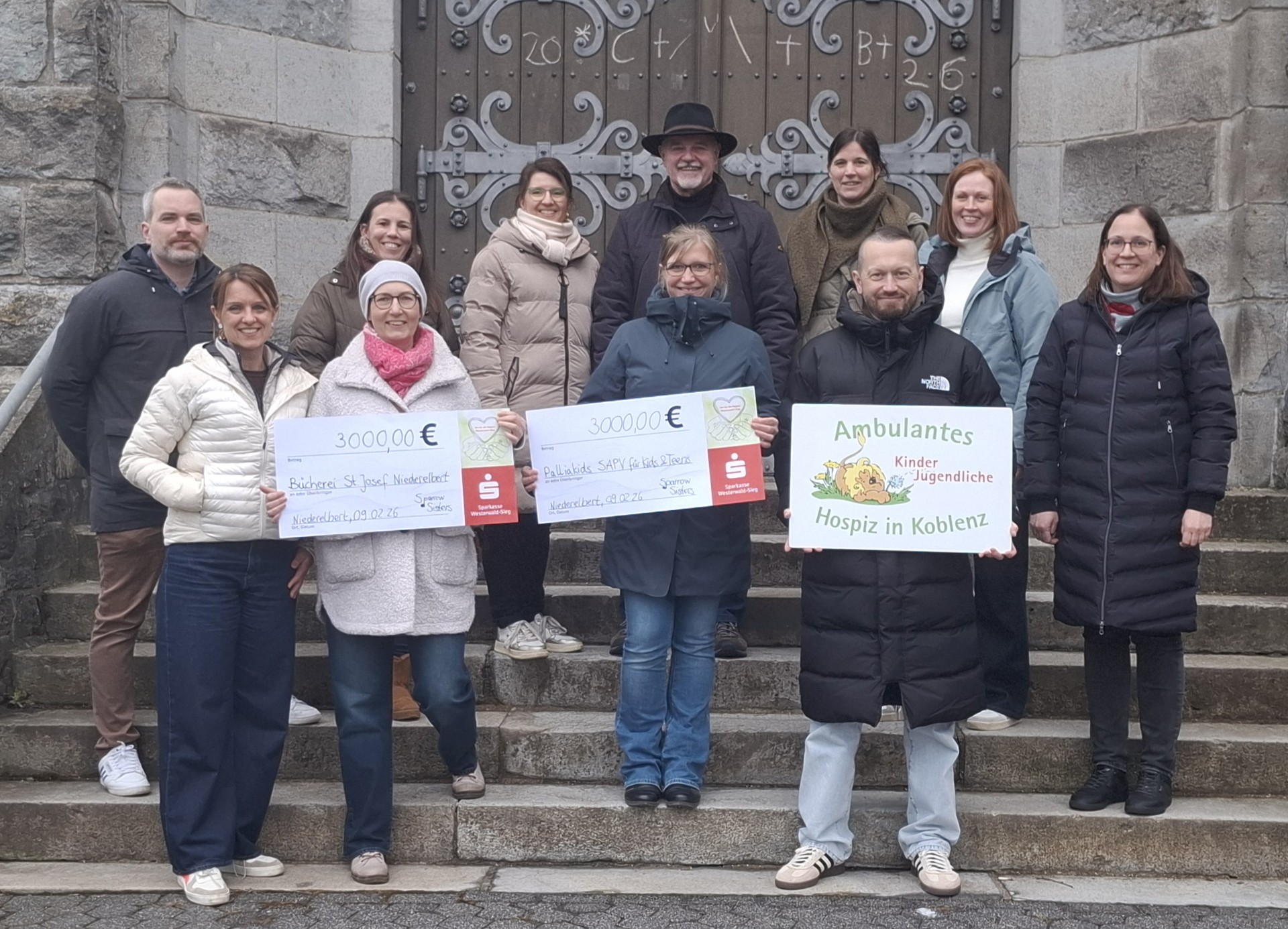 Menschen auf einer Treppe, die Schilder mit Spendenbeträgen hochhalten
